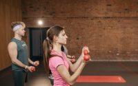 Group of adults exercising indoors with dumbbells, focused on fitness and health.